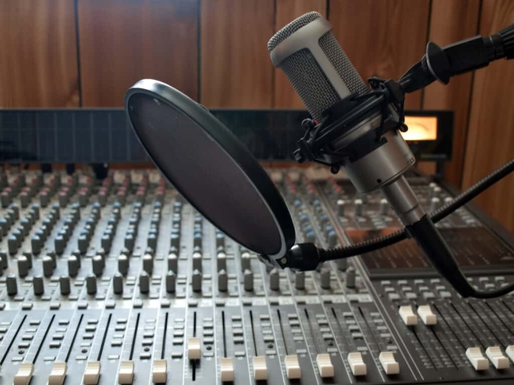 a studio vocal microphone over a mixing board console. A/V/L Provider
